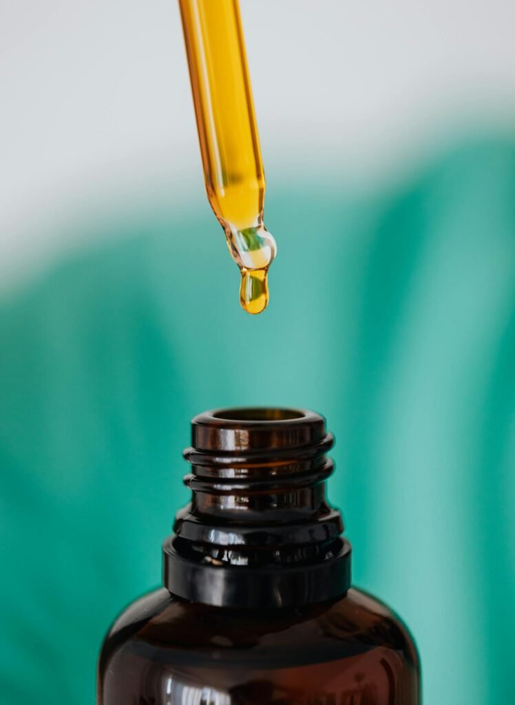 Closeup of anonymous doctor with pipette for fluid dripping yellow medication in brown glass vial while making procedure in clinic
