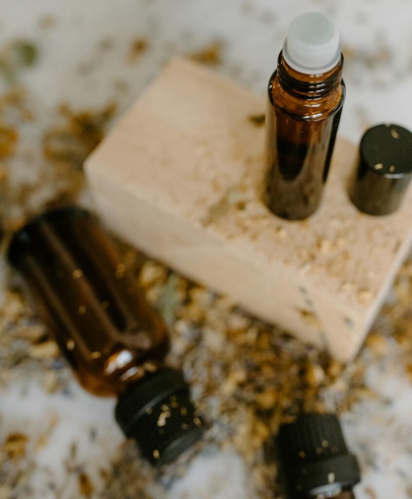 Brown glass roller bottles for essential oils on a wooden block surrounded by natural elements.