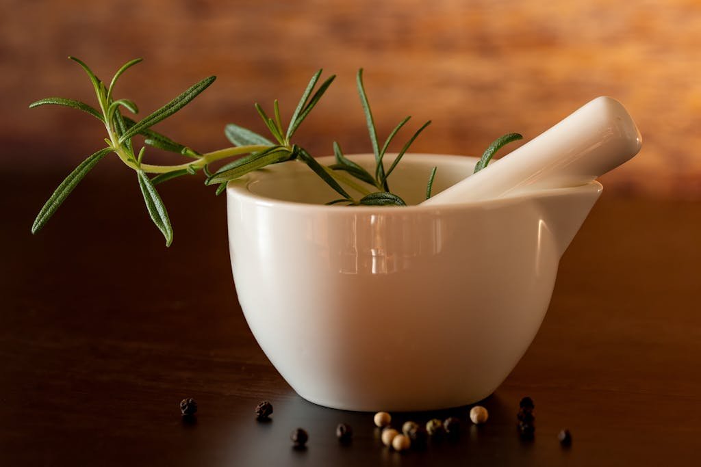 Elegant white mortar with pestle and rosemary on wooden background, perfect for culinary themes.