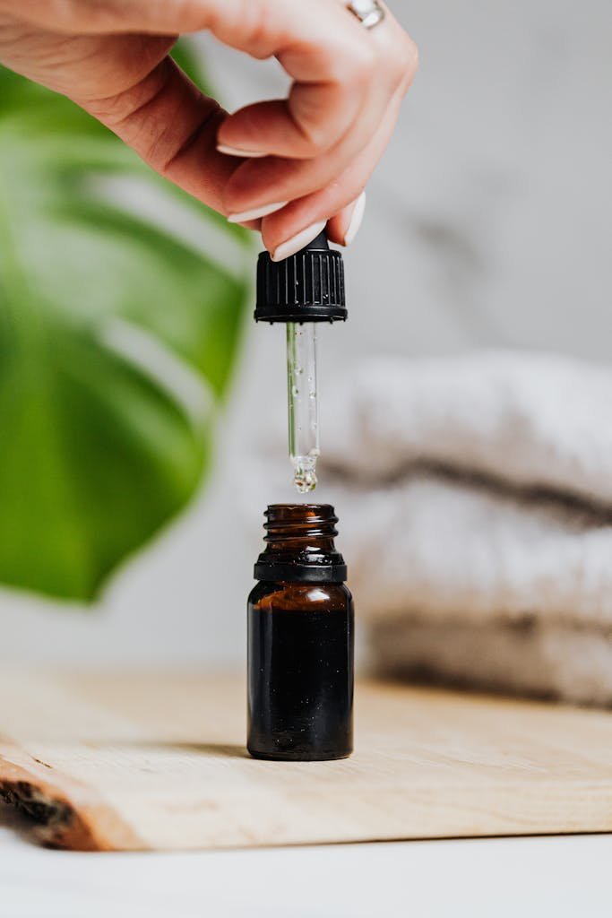 Luxury skincare serum dropper over brown glass bottle on wooden board.