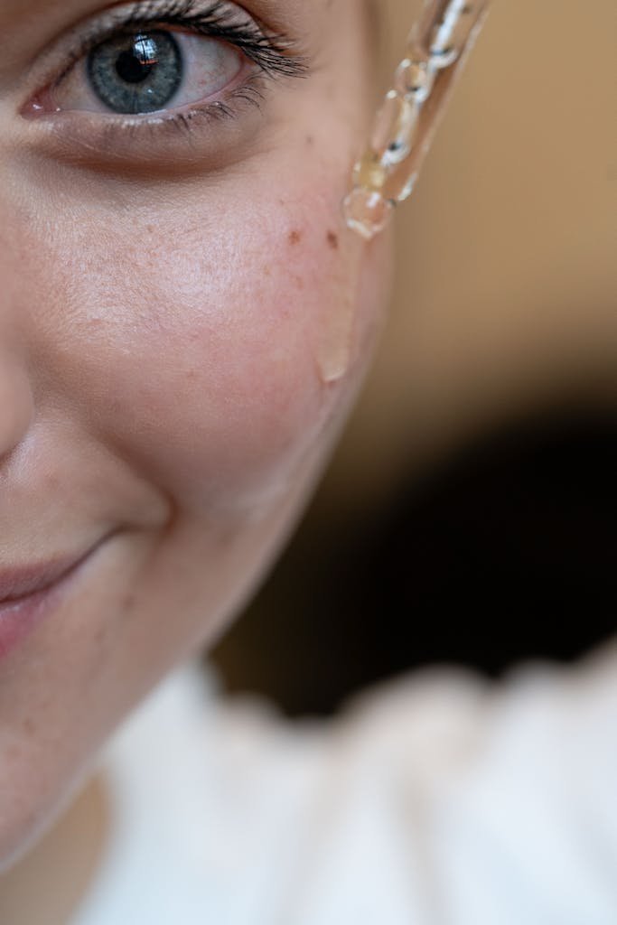 Close-up image of a person applying skincare serum using a dropper.