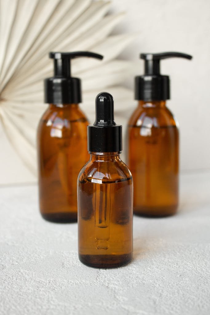 Stylish arrangement of amber glass cosmetic bottles with droppers and pumps on a textured surface.
