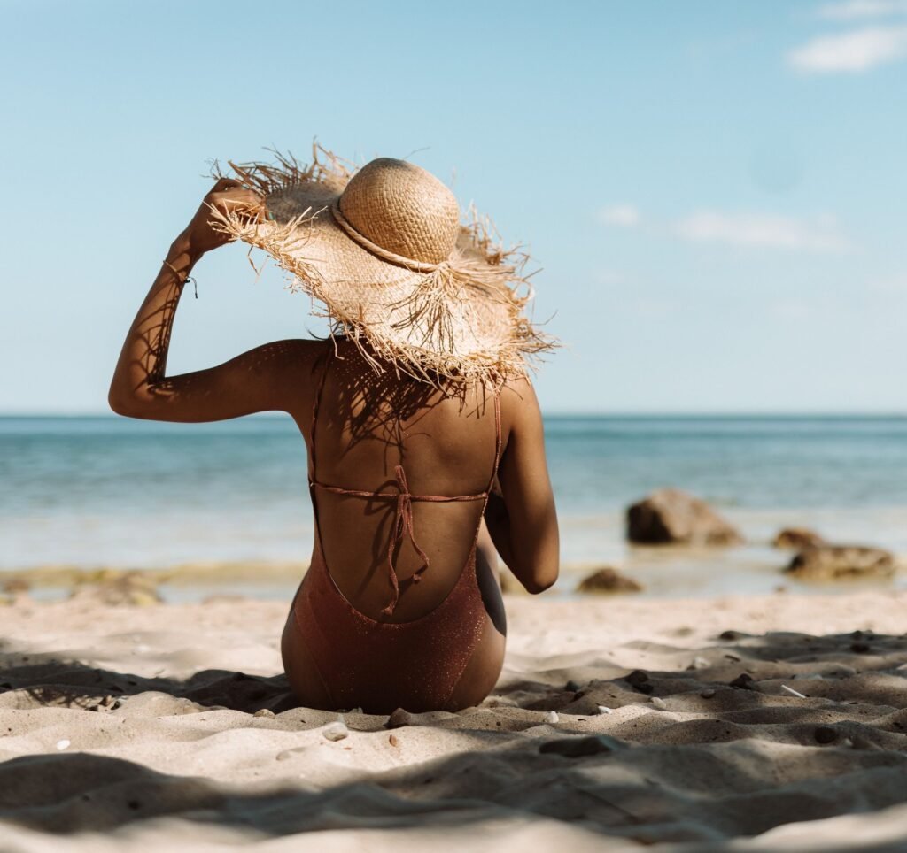 Back view of woman in straw hat enjoying a sunny day at the beach.