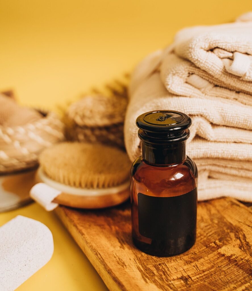 Elevate your self-care routine with these essential bath products, featuring a glass bottle, natural brush, and soft towels.