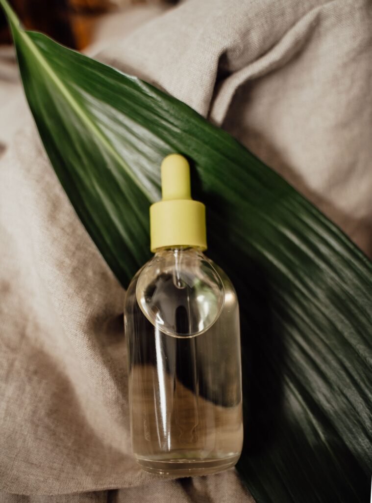 Glass dropper bottle of cosmetic serum on a green leaf for eco-friendly skincare.