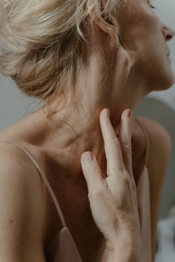 Graceful close-up capturing a woman's hands gently touching her neck with serene elegance.
